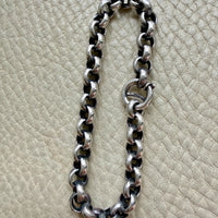 Silver chain bracelet on a textured beige surface