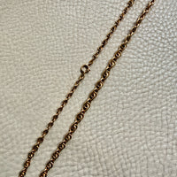 Gold chain necklace on a textured light gray background