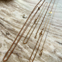 Gold watch chain necklaces on a marble surface
