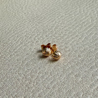 Gold earrings on a light gray textured surface