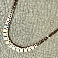 gold necklace on a textured beige background