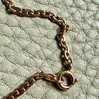 Gold chain necklace on a light green textured surface