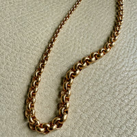 Gold chain necklace on a light gray textured background