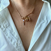 Gold necklace with charms pendant worn by a person in a white shirt