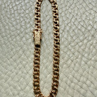 18k Gold chain bracelet on a textured light gray surface
