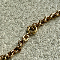 Gold chain bracelet on a light gray textured surface