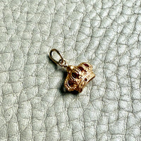Gold crown charm on a textured light gray surface