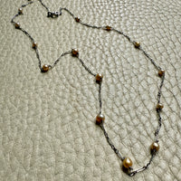 french antique platinum Necklace with pearl beads on a textured beige surface