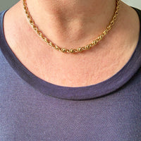 Gold chain necklace worn by a person with a black shirt