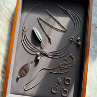 Jewelry set including necklaces and earrings displayed in a wooden box on a marble surface.