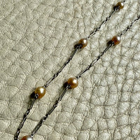 french antique platinum Necklace with pearl beads on a textured beige surface