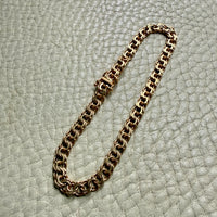 18k Gold chain bracelet on a textured light gray surface