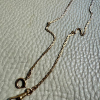 Gold chain with clasp on a textured gray surface. Penelope Penelope Vintage 18k gold fine jewelry