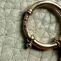 18k Gold antique bolt ring jewelry clasp piece on a textured light gray background