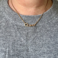 Gold necklace worn by a person in a gray sweater