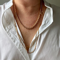 Person wearing a white shirt with gold chain necklaces.
