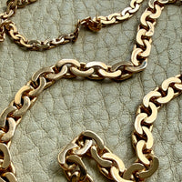 Gold chain necklaces on a textured green surface