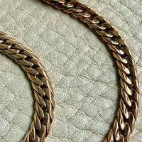 18k vintage Gold curb chain bracelet on a textured light gray surface penelopepenelope.com