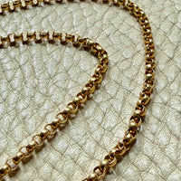18k Gold antique rolo link necklace on a textured light gray surface