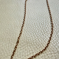Gold chain necklace on a textured beige surface