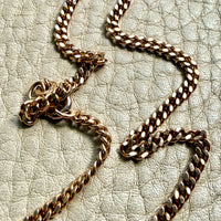 Gold chain necklace on a textured beige surface