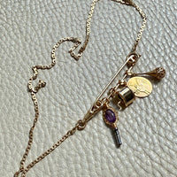 Gold necklace with charms on a textured light gray background