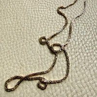 14k gold Gold byzantine chain necklace on a textured beige surface penelopepenelope.com fine jewelry