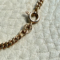 Gold chain bracelet on a light gray textured background