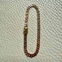 Gold chain bracelet on a light gray textured surface