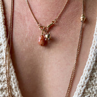Necklace with a pendant on a person wearing a white knit cardigan.