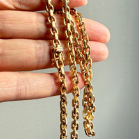 vintage 18k Gold biker chain held by a hand against a gray background
