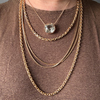 Gold chain necklaces with a central pendant on a brown shirt penelopepenelope.com