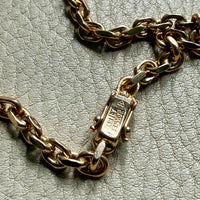 18k Gold biker link chain bracelet with a clasp on a textured surface. Penelope Penelope vintage gold jewelry