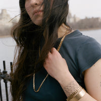 Woman wearing a gold necklace and bracelets with a blurred background