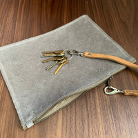 Simple leather zipper pouch to keep you organized. Bovine suede. Measures 10” x 7” Metal zip with donut pull. Attach a wrist strap to zipper tab to make this into a clutch.