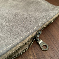 Simple leather zipper pouch to keep you organized. Bovine suede. Measures 10” x 7” Metal zip with donut pull. Attach a wrist strap to zipper tab to make this into a clutch.