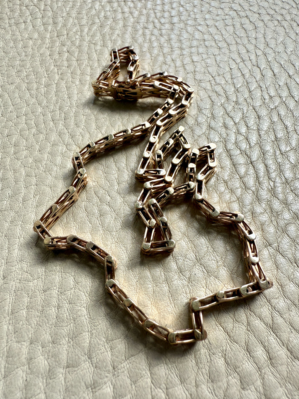 gold chain necklace on a textured light gray surface
