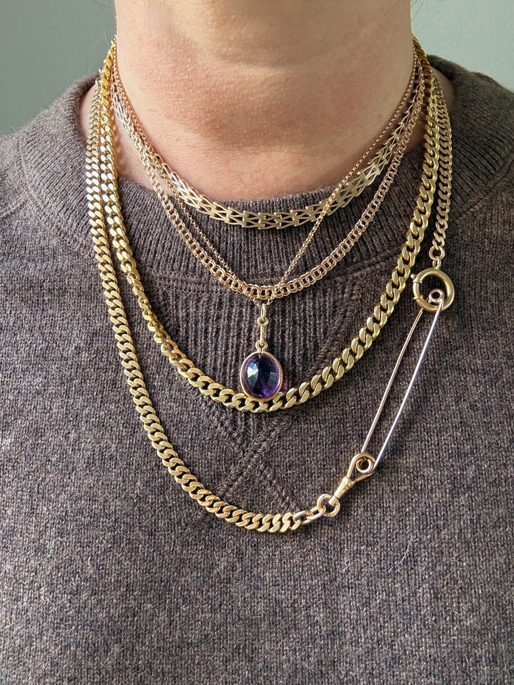 Gold chain necklace with a pendant on a brown sweater