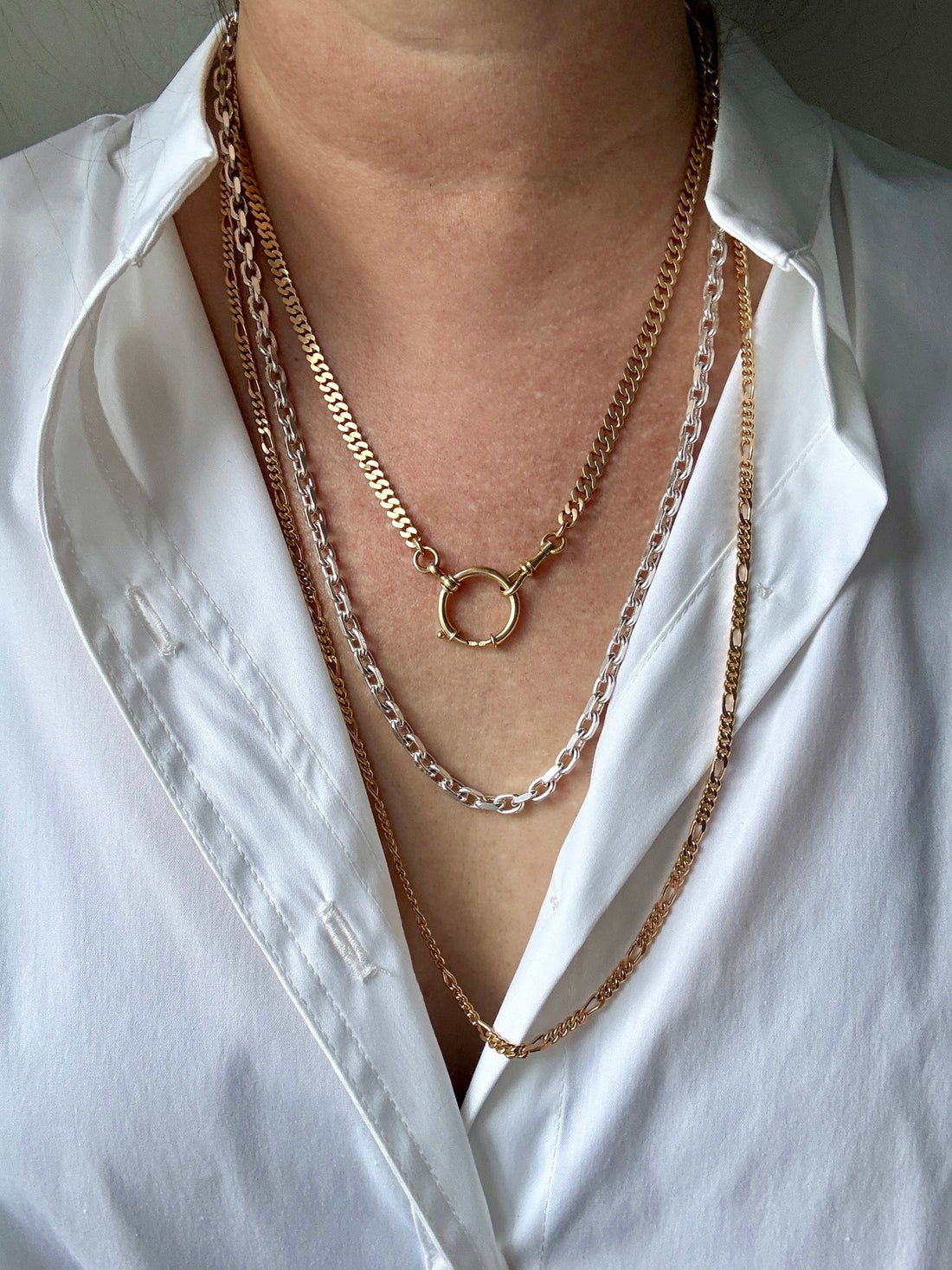 Layered gold necklaces on a white shirt