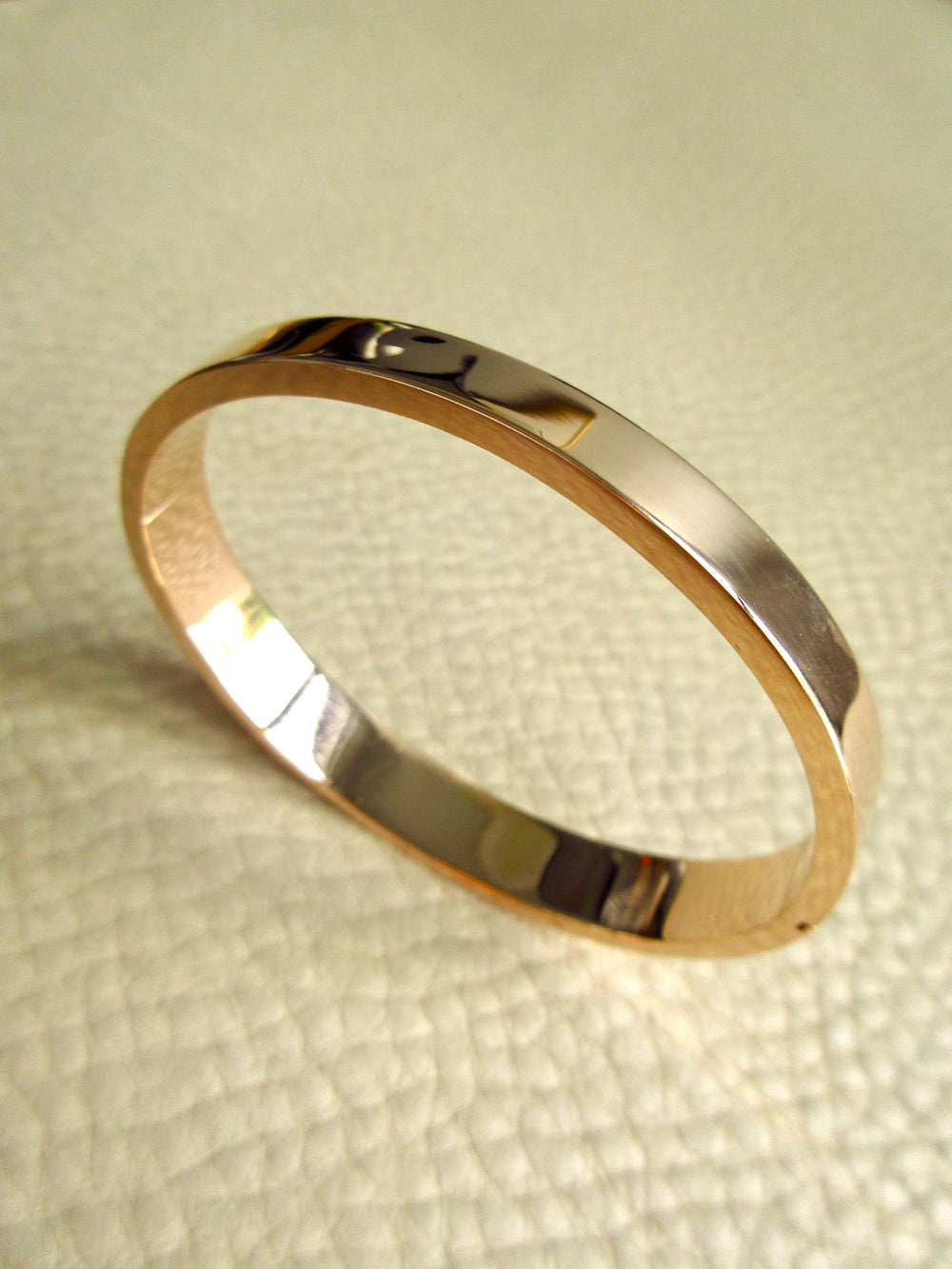 high polish 14k gold vintage hinged bangle on beige leather background