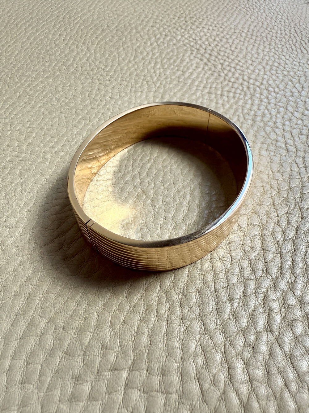 Gold bangle on a textured beige surface