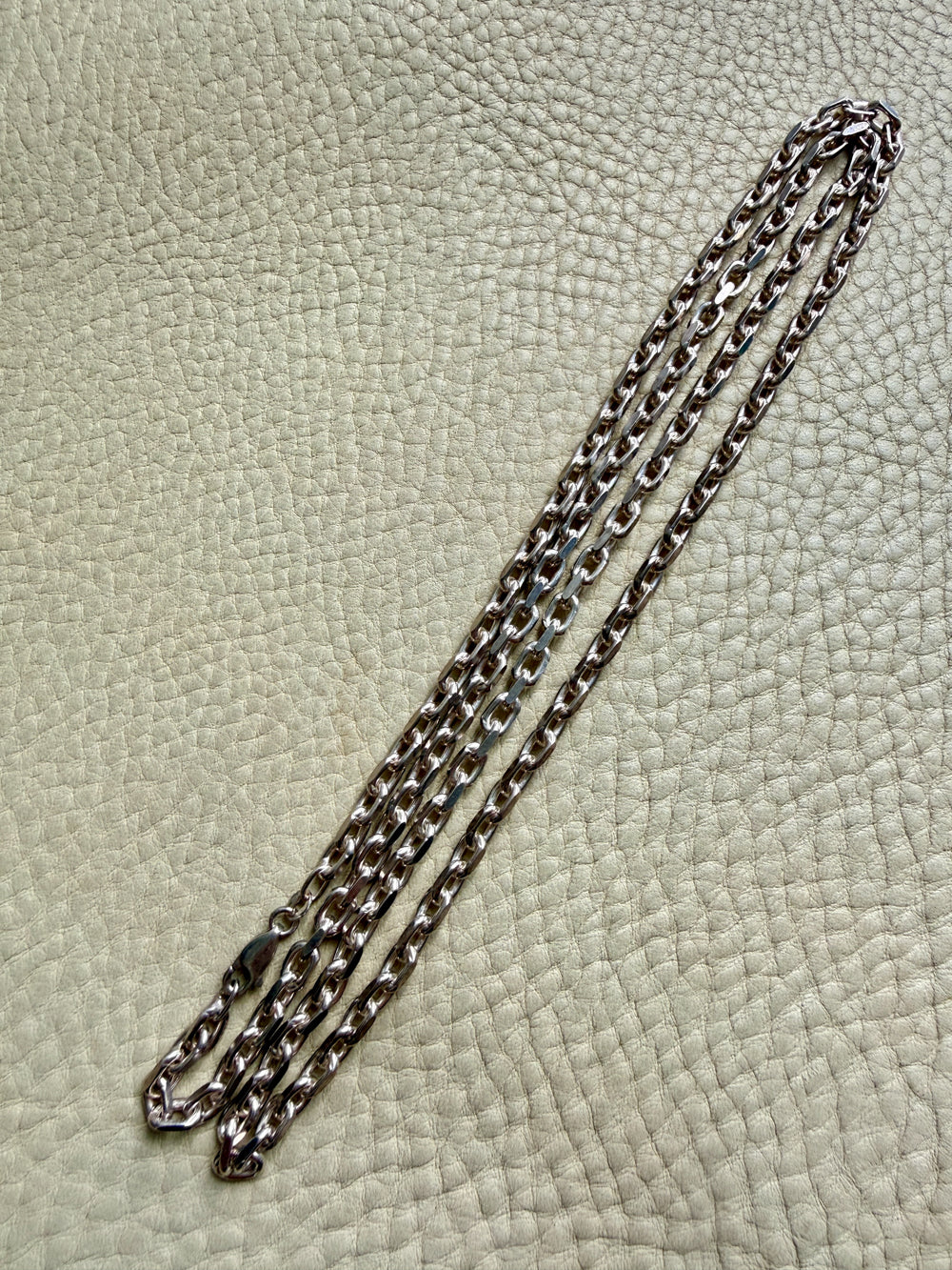 Silver chain on a textured beige surface