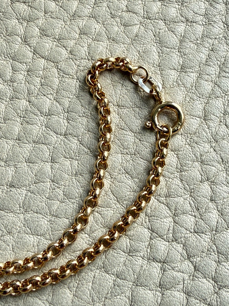 Gold chain necklace on a textured light gray surface