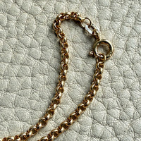 Gold chain necklace on a textured light gray surface