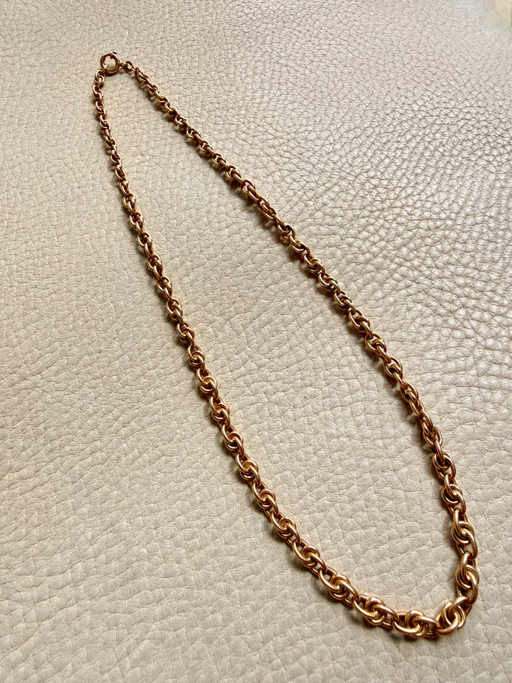 Gold chain necklace on a textured beige surface