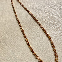 Gold chain necklace on a textured beige surface