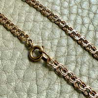 Gold chain bracelet on a textured light green surface
