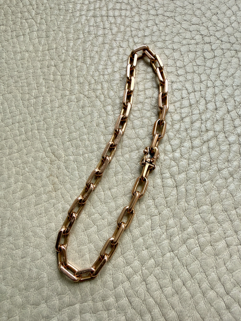 18k Gold chain bracelet on a textured light green surface