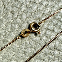 Gold chain necklace on a textured light gray surface
