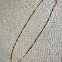 Gold chain necklace on a textured light gray surface